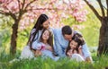 Young parents with small daugthers sitting outside in spring nature. Royalty Free Stock Photo