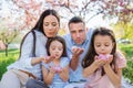 Young parents with small daugthers sitting outside in spring nature. Royalty Free Stock Photo