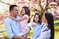 Young parents with small daugthers standing outside in spring nature. Royalty Free Stock Photo