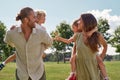 Young parents smiling at each other while giving piggyback ride to their little kids. Family walking in green summer Royalty Free Stock Photo