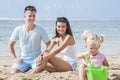 young parents smiling while looking at their little daughter playing sand toys Royalty Free Stock Photo