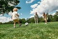 Young parents teaching their little son playing football on grass field in the park on a summer day Royalty Free Stock Photo