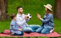 Young parents and their child playing with soccer ball during picnic in countryside Royalty Free Stock Photo