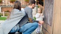 Young parents with their cute little girl drawing on blackboard. Child holding chalk and drawing. Royalty Free Stock Photo