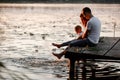 Young parents and their little son sitting on the wooden pier near the lake, at sunset on summer day Royalty Free Stock Photo