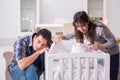 The young parents with their newborn baby near bed cot Royalty Free Stock Photo