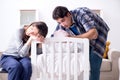 The young parents with their newborn baby near bed cot Royalty Free Stock Photo