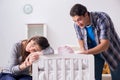 The young parents with their newborn baby near bed cot Royalty Free Stock Photo