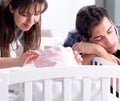 Young parents with their newborn baby near bed cot Royalty Free Stock Photo