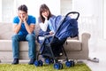 The young parents with their newborn baby in baby pram sitting on the sofa