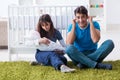 The young parents with their newborn baby sitting on the carpet