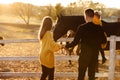 Young parents walk with little daughter near horses in autumn park. Dad and mom holding baby girl. Happy family concept Royalty Free Stock Photo