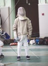 Young participant of the fencing tournament in white clothes and protective mask on the fencing tournament