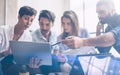 Young partners making research for new business direction. Young businessman working modern laptop and showing documents Royalty Free Stock Photo