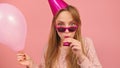 Young party woman blowing party horn whie holding balloon. Isolated on pink background Royalty Free Stock Photo