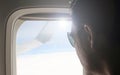 Young passenger looking out through window of the flying airplane. Side view of handsome man against plane window sitting and