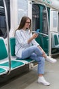 Passenger young woman using mobile smart phone chatting in social networks in subway train at metro Royalty Free Stock Photo