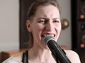 young passionate woman singing in a microphone in a studio. vocal audio song recording. professional singer