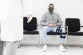 Young patient with face mask in a waiting room of a hospital looking at a doctor Royalty Free Stock Photo