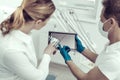 Young patient looking at the screen of the tablet in a dental cabinet