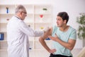 Young male patient visiting old male doctor in vaccination conce Royalty Free Stock Photo