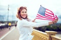 Young patriot woman with toothy smile enjoying stretching USA flag