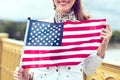 Young patriot woman with toothy smile stretching USA flag concept