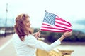 Young patriot woman with toothy smile stretching USA flag profile view
