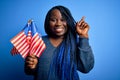 Young patriotic african american plus size woman with braids holding united states flags surprised with an idea or question