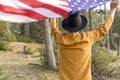 Young patriotic man in cowboy hat waving United States American flag in forest.Beautiful woodland landscape at sunset.Independence Royalty Free Stock Photo