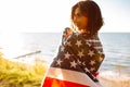 Young patriotic woman holds American flag in the wind on the beach on a sunset. 4th July, Independence day. Freedom, american