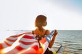 Young patriotic woman holds American flag in the wind on the beach on a sunset wearing medical protictive mask. 4th July,