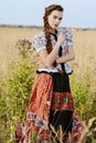 Young peasant woman, dressed in Hungarian national costume, posing over nature background