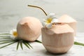 Young peeled coconut with straw and flowers on white marble table. Space for text Royalty Free Stock Photo