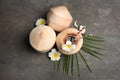 Young peeled coconuts with straw, palm leaf and beautiful flowers on grey table, flat lay Royalty Free Stock Photo