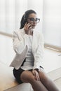 Young pensive business woman in white jacket talking by mobile phone. Royalty Free Stock Photo