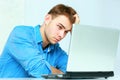 Young pensive businessman sitting at the table with laptop Royalty Free Stock Photo