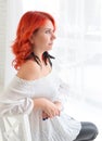 A young pensive Caucasian girl in profile at the window looking into the distance Royalty Free Stock Photo