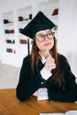 Young pensive caucasian woman college student in graduation outfit , sitting in front laptop with books and thinking about future Royalty Free Stock Photo