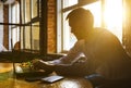 Young pensive coworker working at sunny work place loft while sitting at wooden table.Man analyze document on laptop display. Royalty Free Stock Photo