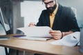 Young pensive coworker working at sunny work place loft while sitting at the wooden table.Man analyze paper document Royalty Free Stock Photo