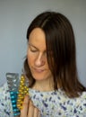 A young pensive girl holding and shows a blue and yellow complex of vitamins and minerals in her hand.