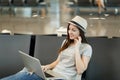 Young pensive traveler tourist woman sitting working on laptop thinking wait in lobby hall at international airport Royalty Free Stock Photo