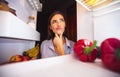 Young pensive woman thinking near opened fridge Royalty Free Stock Photo