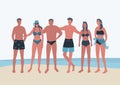 Young people in beach suits stand on the seashore. Young women and young men in swimsuits and swimming trunks