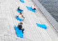 Young people on blue seats on the Bolotnaya embankment