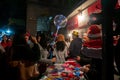 Young people buying red hats and other festive gifts at roadside stall and enjoying themselves at illuminated and decorated park