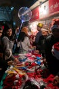 Young people buying red hats and other festive gifts at roadside stall and enjoying themselves at illuminated and decorated park