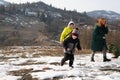 Young people and children play outdoors in winter on the snow in the highlands.