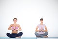 Young people do yoga sitting in lotus position indoors. Women hands in meditating gesture Royalty Free Stock Photo